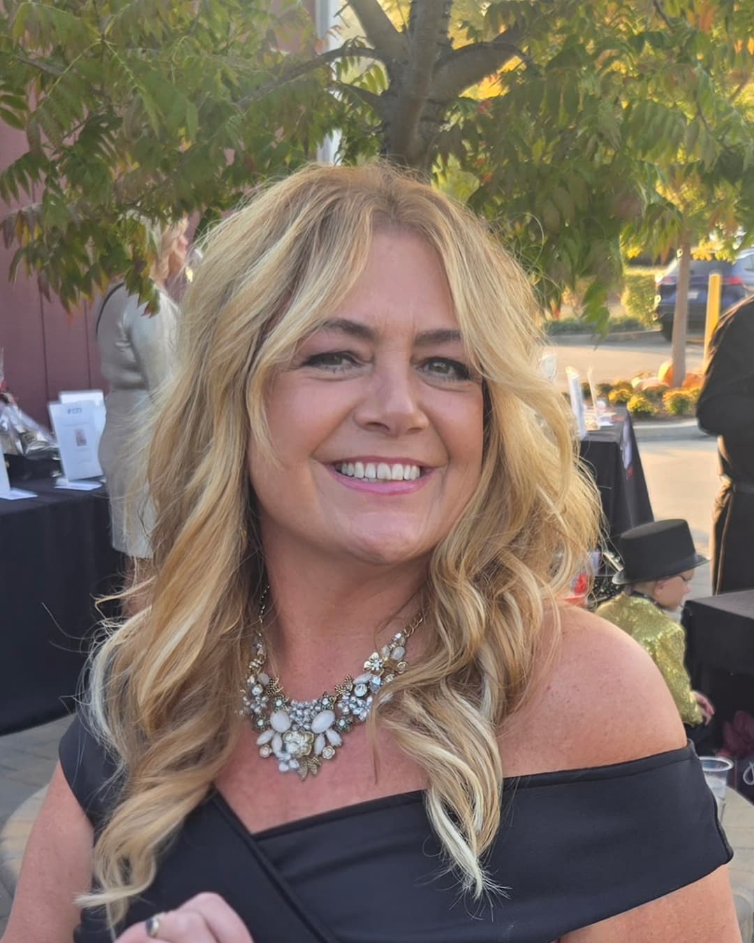 Becky, founder and creative director of Revel & Rare Occasions, smiling in a black off-the-shoulder dress