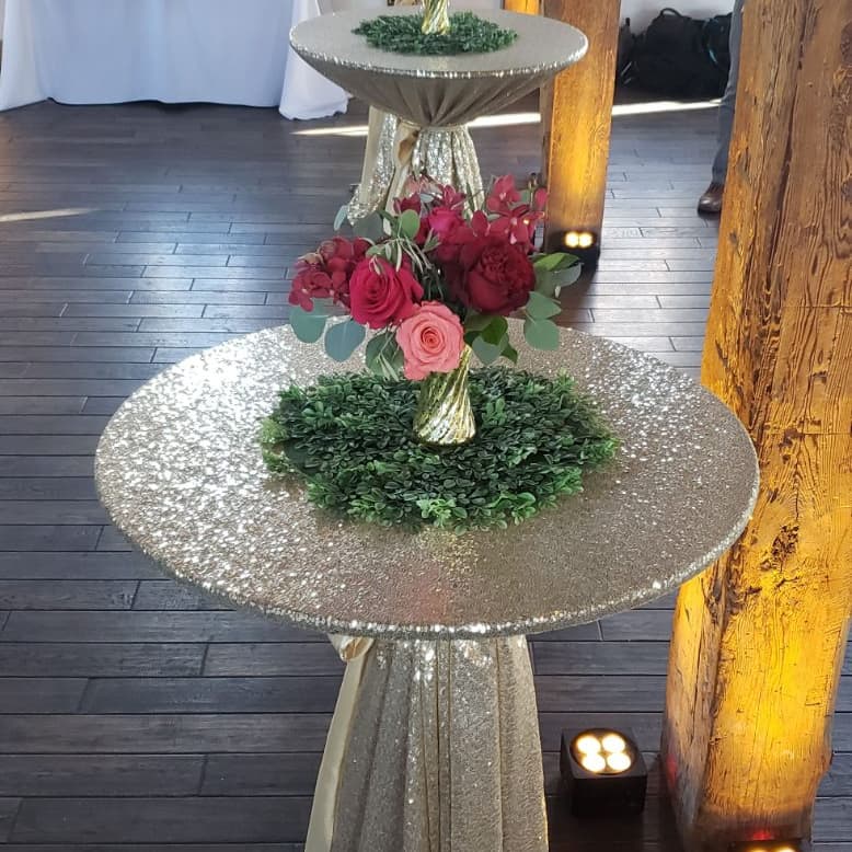 Tiered floral stand on a sequined cocktail table inside a stone barn