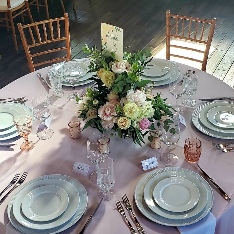 Place settings with sage napkins and a blush floral centerpiece