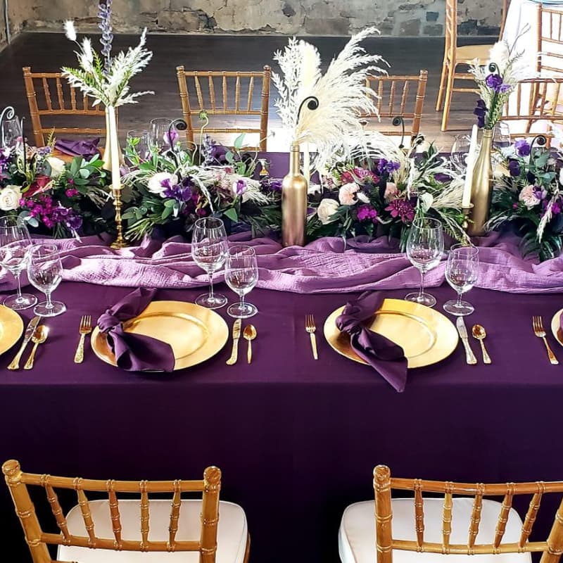 Head table draped in purple linen with florals and candles