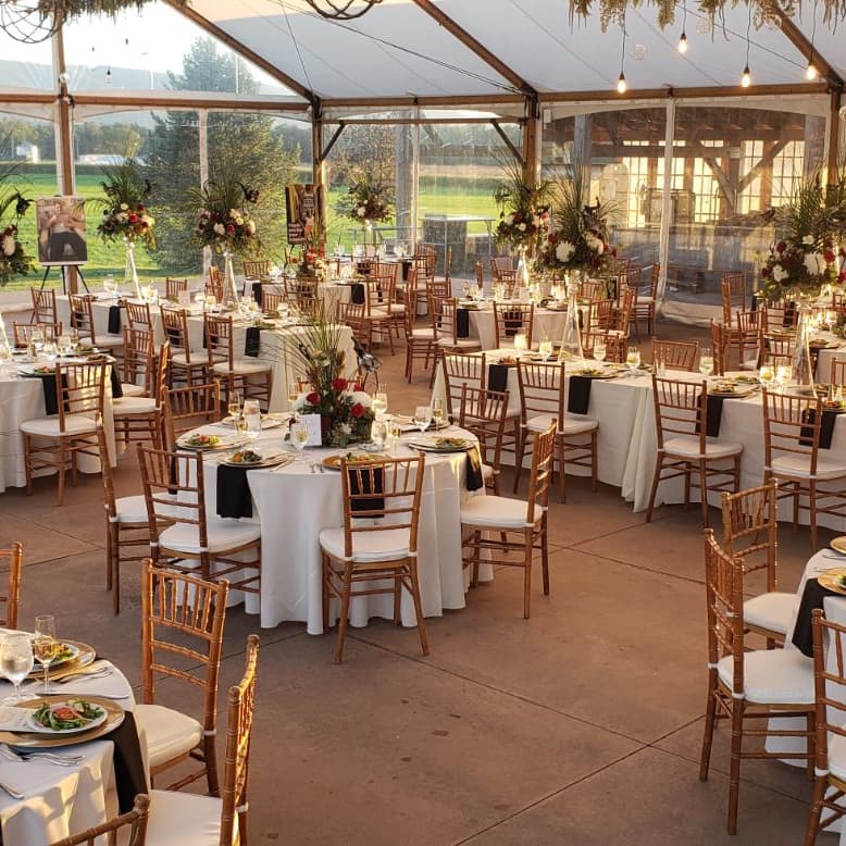 Tented reception with round tables, white linens and floral centerpieces