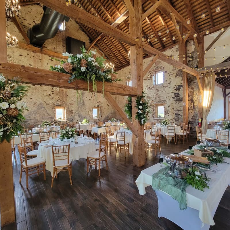 Barn reception with long tables, greenery runners and string lights overhead