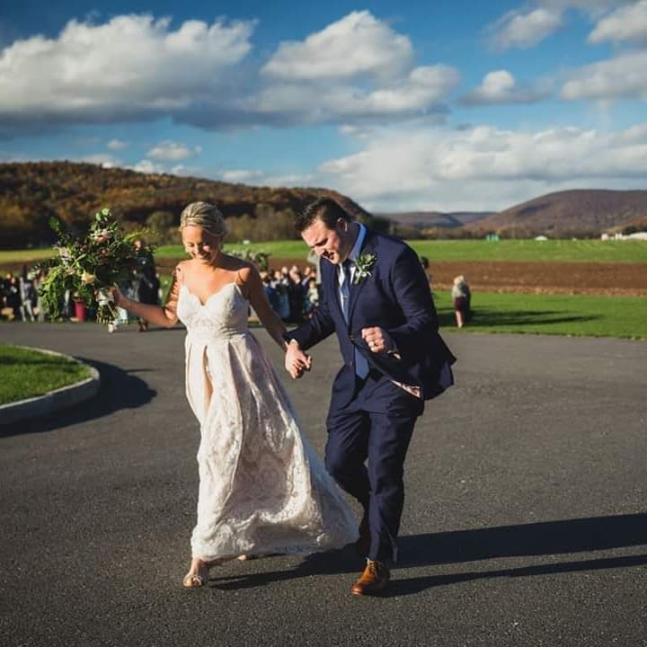 Newlyweds walking hand in hand along a country road at sunset