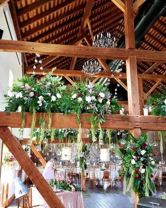 Timber-beamed hall dressed with hanging greenery, white florals and crystal chandeliers