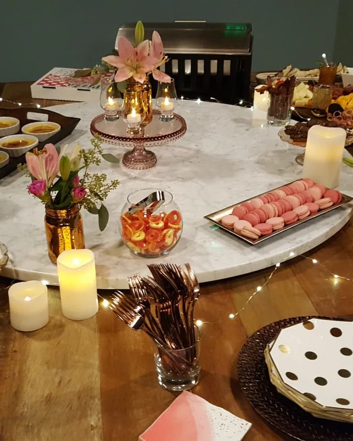 Dessert and appetizer spread with candles and fresh lilies on a marble lazy susan